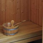 Holzsauna mit Sitzbank und traditionellem Eimer mit Löffel.