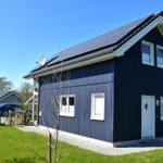 Ein zweistöckiges Haus mit Solaranlage auf dem Dach und weißer Tür.