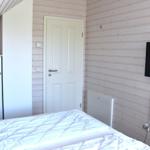 Schlafzimmer mit Bett, Kleiderschrank und Wandfernseher an Holzwand.