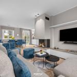 Wohn- und Essbereich mit Kamin, TV und blauen Sesseln.