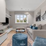 Wohnzimmer mit Kamin, Sofa und Fenster. Wandbilder und blauer Sitz.