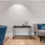 Ein Wohnbereich mit blauen Sesseln, einem grauen Sofa und einem Tisch.