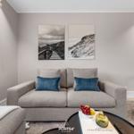 Wohnzimmer mit grauem Sofa, blauen Kissen und Wandbildern