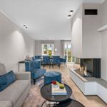 Wohn- und Essbereich mit Kamin und blauen Sitzgelegenheiten.