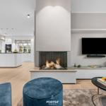 Wohnzimmer mit Kamin, Fernseher und Küchenbereich im Hintergrund.