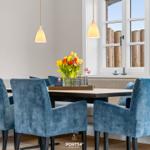 Esszimmer mit blauen Stühlen, Tisch und Blumen vor Fenster