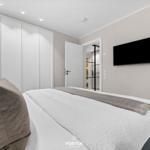 Schlafzimmer mit Bett, Kleiderschrank und Wandfernseher