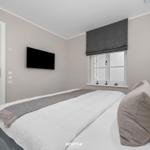 Schlafzimmer mit Bett, Fenster und Wandfernseher.