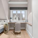 Schlafzimmer mit Schreibtisch und Fensterblick auf Dächer.