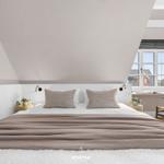 Schlafzimmer mit Dachschrägen, großem Bett und Fensterblick.