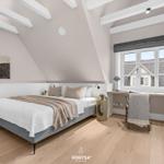 Schlafzimmer mit Dachschrägen, Bett, Schreibtisch und Fenster mit Blick.