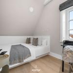 Schlafzimmer mit Dachschrägen, Bett, Schreibtisch und Fenster.