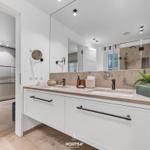 Badezimmer mit Doppelwaschbecken, Spiegel und Sauna im Hintergrund.