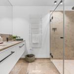 Badezimmer mit Dusche, Waschbecken und Heizkörper