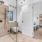 Dusche mit Duschbrause, Toilette und Blick in Schlafzimmer mit Sauna.