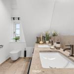 Badezimmer mit Doppelwaschbecken, Toilette und Fenster