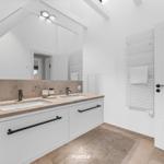 Doppelwaschbecken mit Spiegeln und Heizkörper an der Wand.