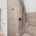 Dusche mit Steinwand und Sitzbank. Blick in angrenzenden Raum.