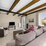 Wohnzimmer mit Sofa, Fernseher und Holzbalken an der Decke.