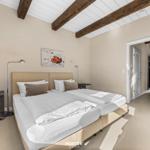 Schlafzimmer mit Doppelbett, Holzbalken und Kunstwerk an der Wand.