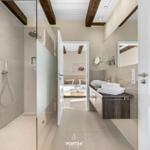 Badezimmer mit Dusche, Waschbecken und Blick in Schlafzimmer.