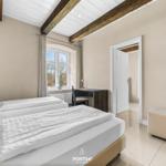 Zwei Betten, Schreibtisch und Fenster mit Blick. Holzbalken an Decke.