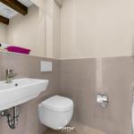 Badezimmer mit Waschbecken, WC und Waschmaschine-Trocknerkombination.