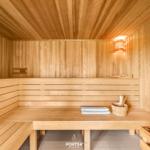 Holzsauna mit Sitzbänken, Handtuch und Eimer.