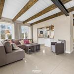 Wohn- und Küchenbereich mit Holzbalkendecke und großem Sofa.