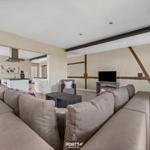 Wohnzimmer mit Sofa, Fernseher und Küchenbereich im Hintergrund.