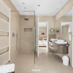 Badezimmer mit Dusche, Waschtisch und Blick in Schlafzimmer