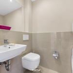 Badezimmer mit Waschbecken, Toilette und Waschmaschine-Trockner-Kombination.