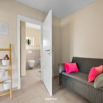 Flur mit Sitzbank und Blick in die Toilette.