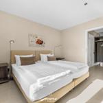 Schlafzimmer mit Doppelbett, Nachttischen und Wandbild. Tür führt zum Bad.