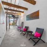 Langgezogene Halle mit Sitzgelegenheiten und Holzbalken an der Decke.