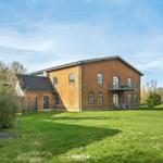 Rotes Backsteinhaus mit Balkon und großem Garten. Modernes Design mit viel Platz.
