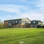 Modernes Haus mit großem Garten und Parkplatz. Ein schwarzes Auto steht vor dem Gebäude.