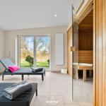 Sauna mit Glaswand, Liegestühle und Blick auf Garten.