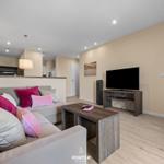 Wohnzimmer mit Sofa, Fernseher und Blick in Schlafzimmer.