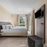 Schlafzimmer mit Doppelbett, TV und Fenster mit Blick auf Garten.