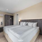 Doppelbett mit weißen Bettwäsche, Nachttische und Kleiderschrank.