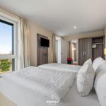 Zimmer mit Doppelbett, Fensterblick und Kleiderschrank.