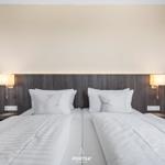 Zwei Betten mit weißen Bettwäschen und Nachttischen mit Lampen.