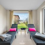 Zwei Liegestühle mit Kissen und Handtüchern vor großem Fenster mit Gartenblick.