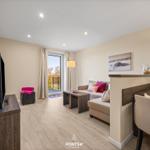 Wohnbereich mit Sofa, TV und Balkonansicht.