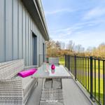Terrasse mit Sitzgruppe und Tisch, Blick auf grünen Rasen und Bäume.