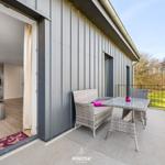 Terrasse mit Sitzgruppe und Blick auf Grünfläche. Durchgang ins Innere mit Küchenbereich.