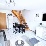 Wohnung mit Küche, Essbereich und Wohnzimmer mit Fernseher und Holztreppe.