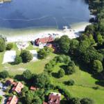 Aussicht auf See mit Strand, Booten und umliegenden Grünflächen.