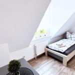 Schlafzimmer mit Dachschrägen, Bett, Nachttisch und Fenster mit Blick.